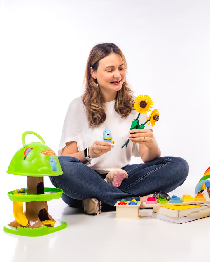 Vanessa sentada com o boneco do Gui e dois girassóis na mão