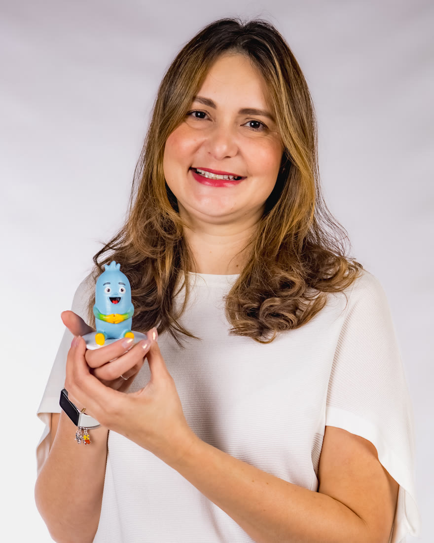 Vanessa Cadena sorrindo, com o boneco do Gui na mão